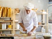 Shutterstock_2747421945_baker uses knife to cut pieces_maiznieks griež gabaliņus ar nazi.jpg