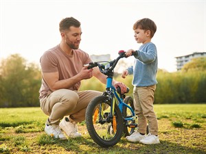 shutterstock_2456195443_father teaching son to ride bicycle_tēvs māca dēlu braukt uz velosipēda.jpg