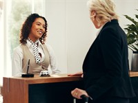 shutterstock_2654945105_smiling woman at front desk_smaidoša sieviete reģistratūrā.jpg