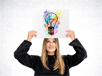 Shutterstock_2467922691_woman showing poster with lightbulb_sieviete, rāda plakātu ar spuldzīti.jpg