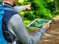 shutterstock_1544931743_Man navigating with tablet computer app on a forest trail_Vīrietis izmanto navigāciju planšetē mežā.jpg