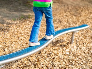 shutterstock_2671729933_Child walking on balance beam in park_Bērns iet pa balansa dēli parkā.jpg