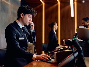 shutterstock_2441452195_receptionist making a phone call_reģistratūras darbinieks runā pa telefonu.jpg